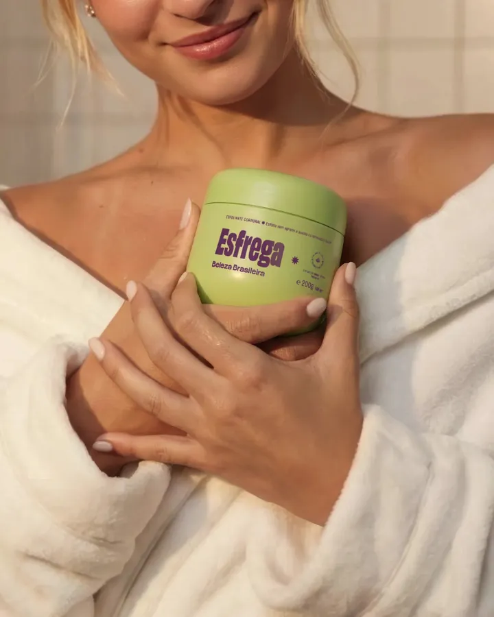 Mulher de roupão segurando o esfoliante Esfrega, da Beleza Brasileira